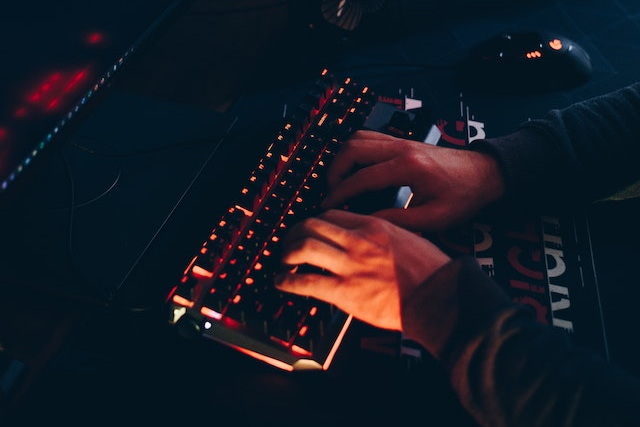 Hands typing on a keyboard in the dark with red backlighting