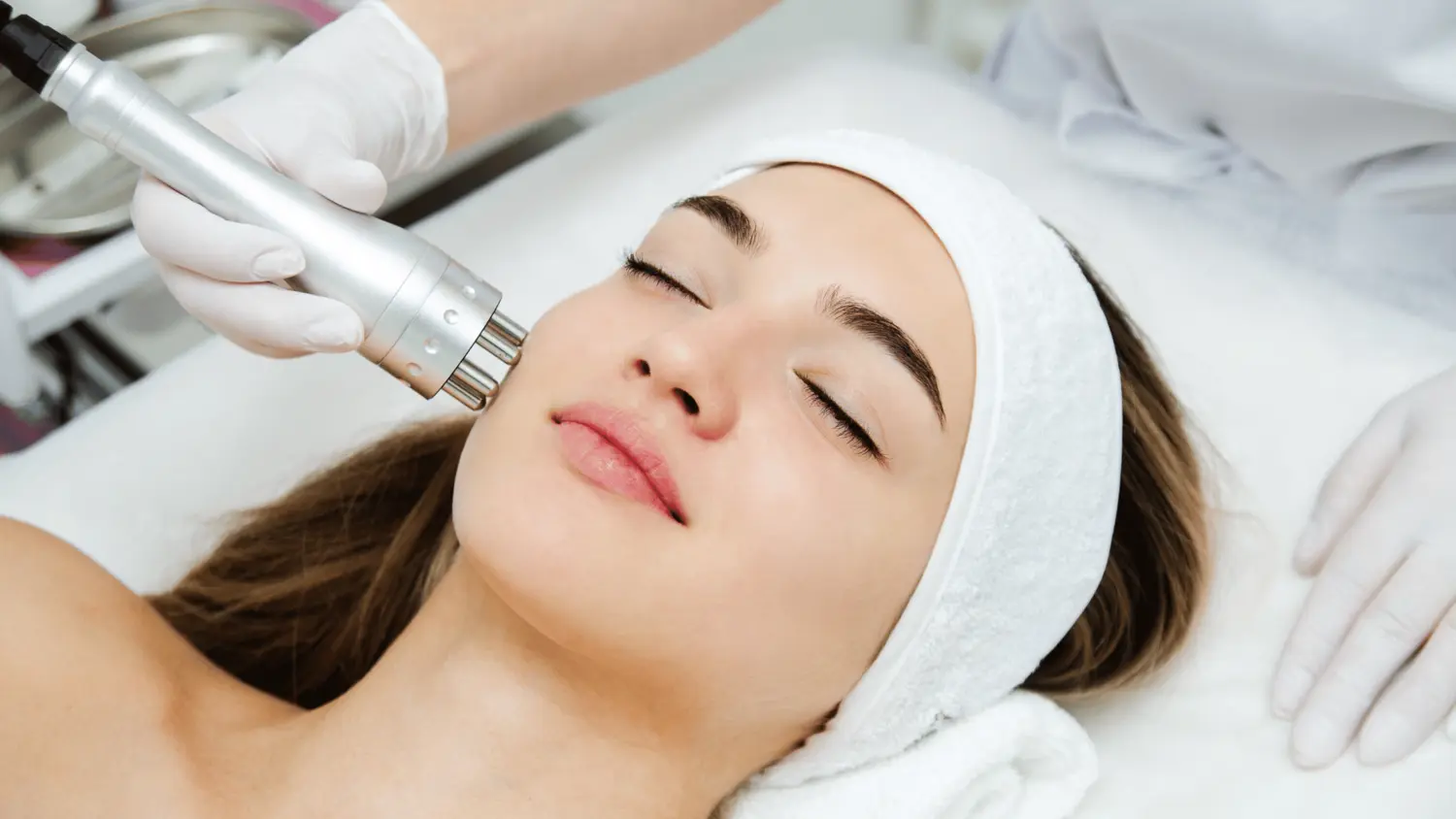 A young woman who looks like a patient of a med spa, receiving facial services 