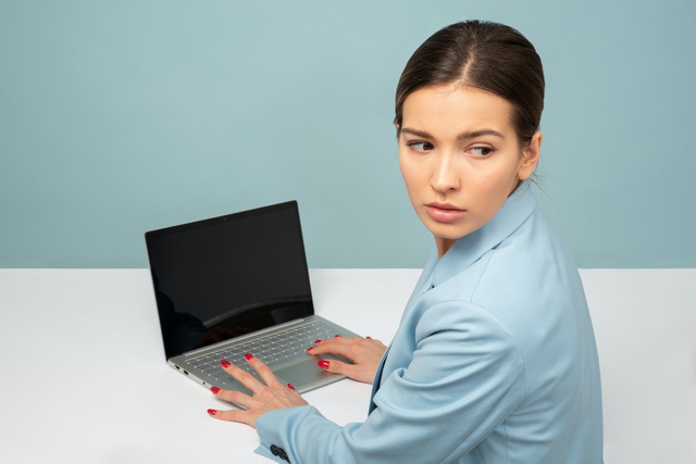 A woman looks over her shoulder as she works on a laptop computer