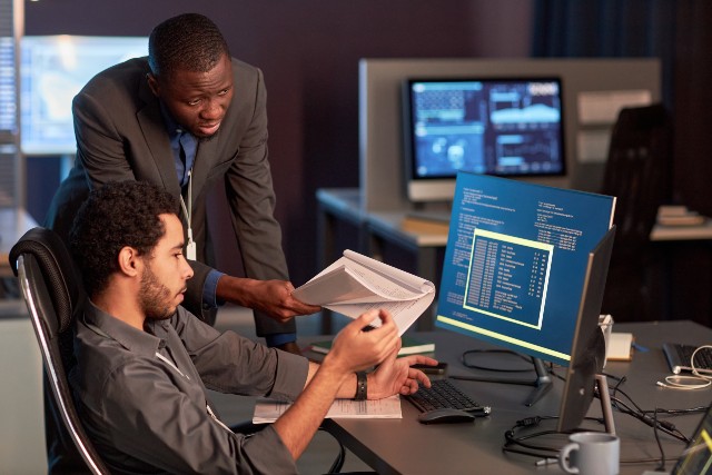 Manager having a discussion with an employee in front of a computer