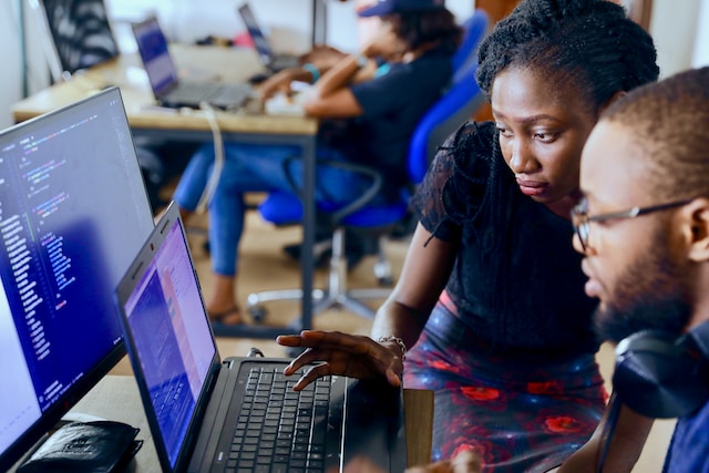 Two employees working on a laptop and a computer at a desk