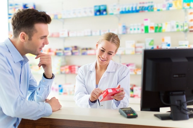 Pharmacy customer picking up a prescription talking to pharmacist