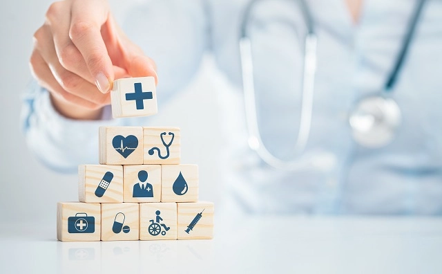Person stacking building blocks with health, medical, and insurance icons
