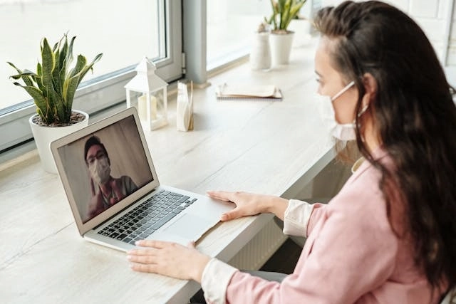 Patient communicating with provider via telehealth wearing a mask during COVID-19